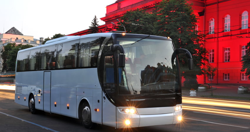 wedding shuttle charter bus driving in front of an illuminated building